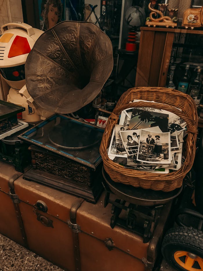 services-02 A nostalgic collection featuring a gramophone, basket of old photographs, and vintage decor items in an antique shop.