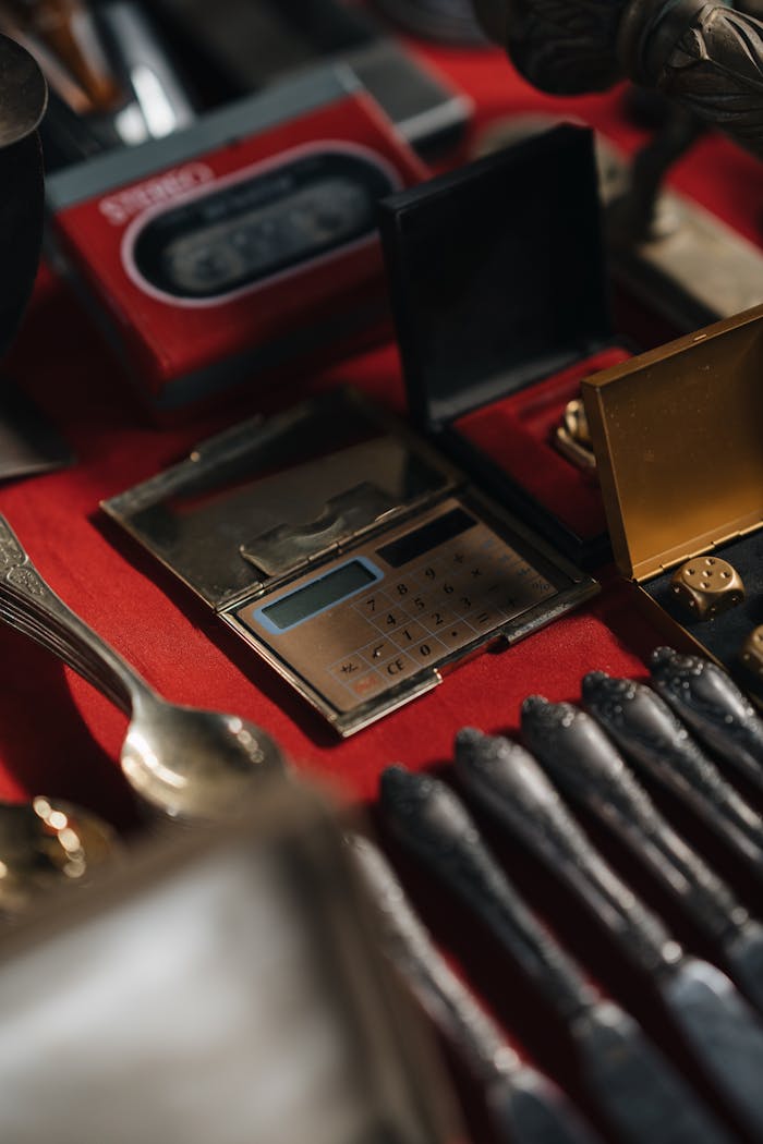 A close-up of retro calculators and cutlery on a red table, exuding a vintage aesthetic.